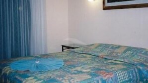 A bedroom with a bed, a nightstand, a wall-mounted lamp, and a window with curtains. - Bulahdelah Myall Motel (Bulahdelah)