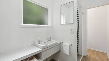 A modern bathroom with a white sink, a mirror, and a window.
