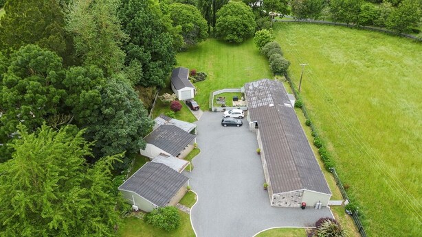 An aerial view of a residential area with houses, a driveway, and surrounding greenery. - Tower Road Motel (Matamata)