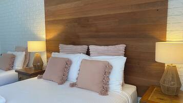 A hotel room with a wooden headboard, two beds with white and beige bedding, and two bedside lamps.