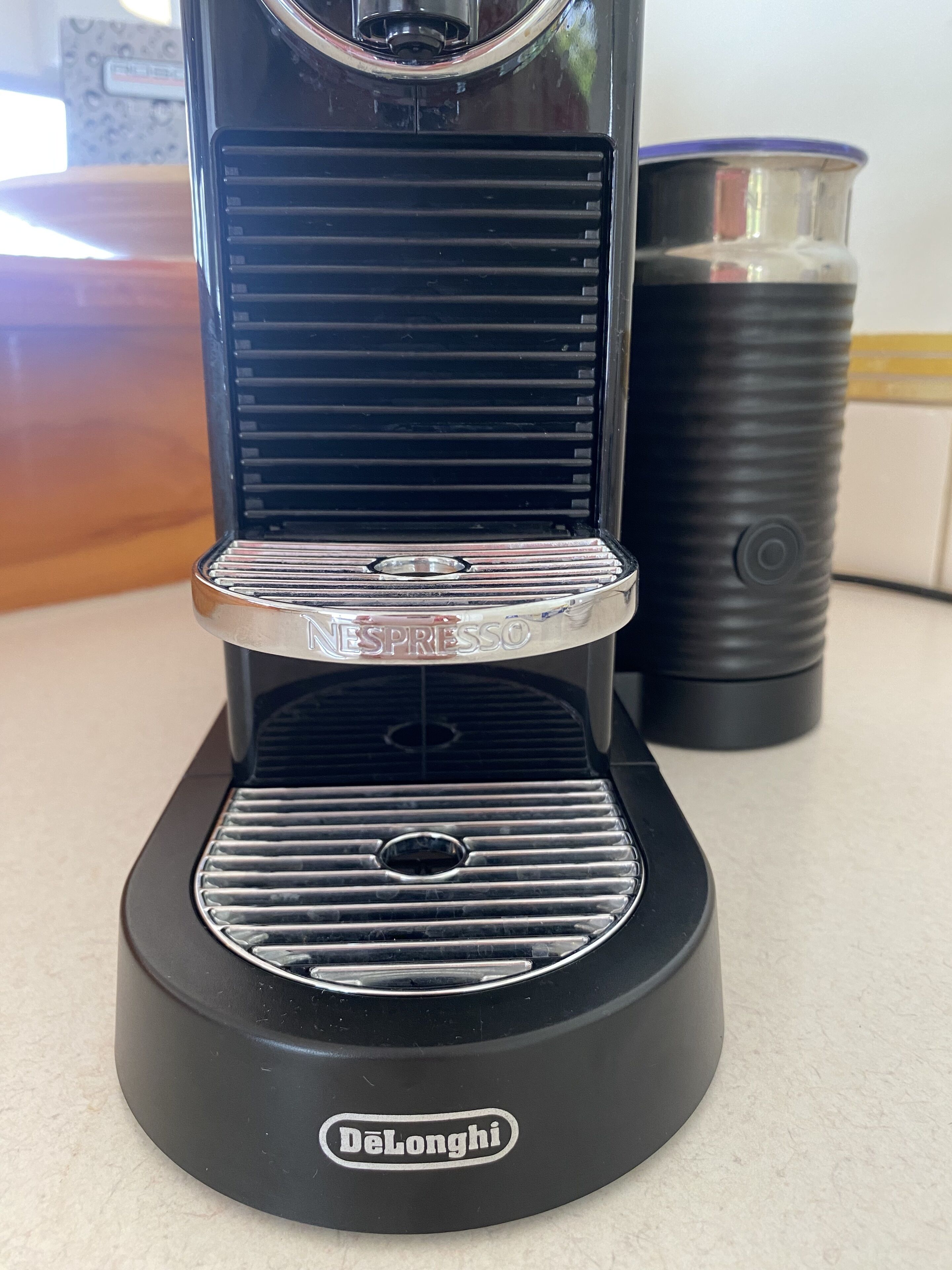 Una máquina de espresso DeLonghi con base negra y detalles plateados, sobre una encimera de cocina.