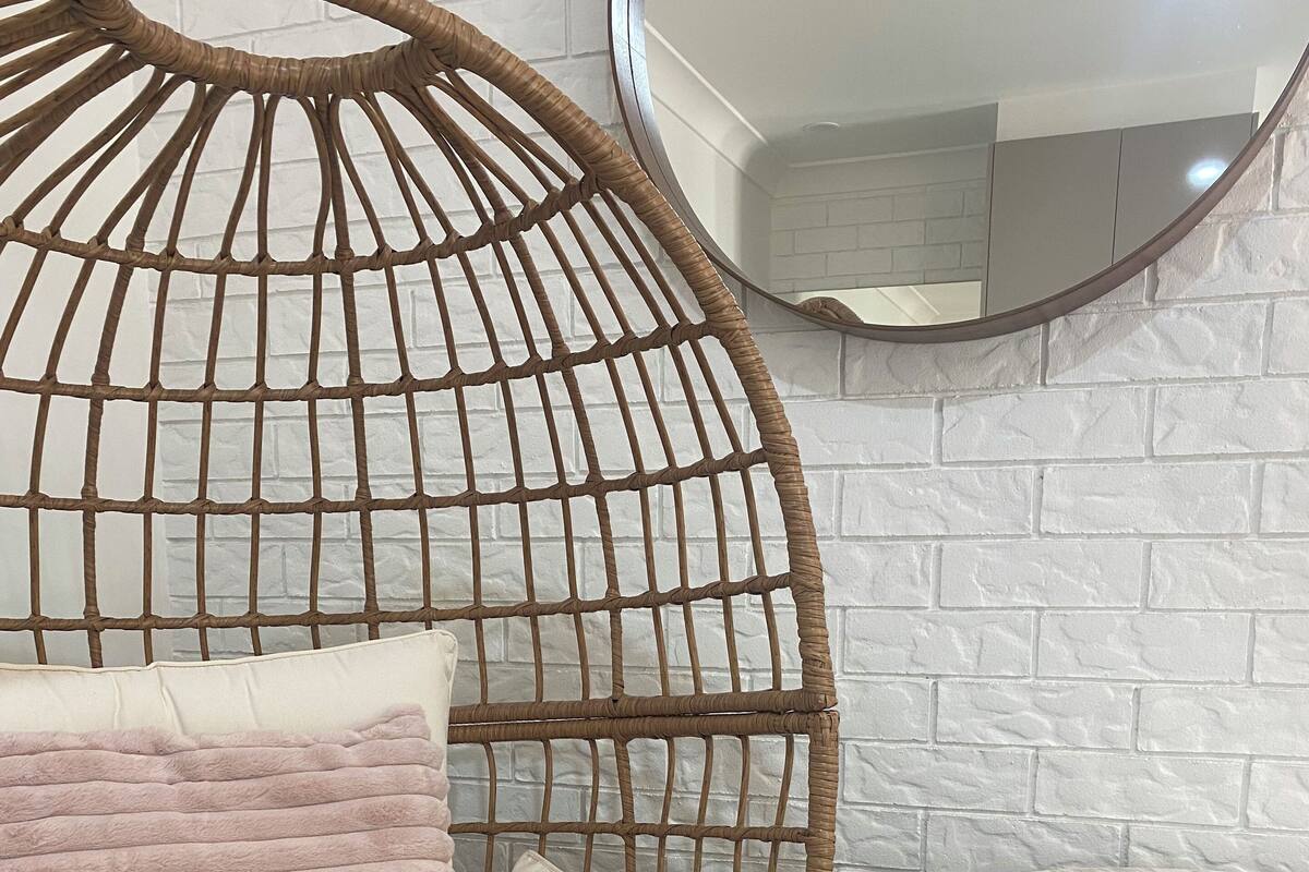 A wicker chair with a cushion and a small round table with a mirror.
