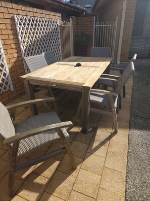 An outdoor patio with a wooden table and wicker chairs.