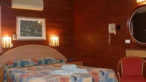 A wooden room with a bed, a chair, and wall-mounted lights. - Mount Kuring-Gai Motel (Mount Kuring-gai)