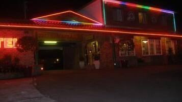A building with a neon sign and a brick facade.
