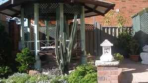 A gazebo with a lattice roof, surrounded by a garden with various plants and flowers. - Mount Kuring-Gai Motel (Mount Kuring-gai)