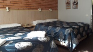 Habitación de hotel con dos camas, una pared de ladrillo y un cabecero.