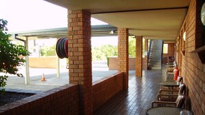 Un espacio de estar al aire libre con techo, paredes de ladrillo, mesas y sillas.