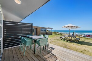 Um deck de madeira com área de estar externa e vista para o oceano.