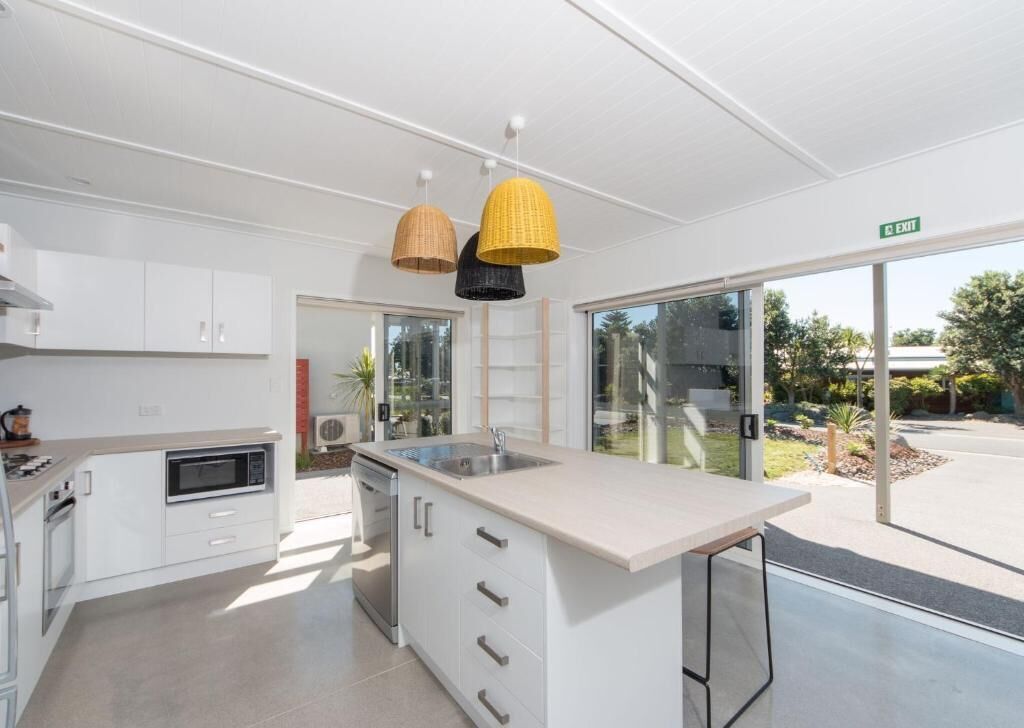 A modern kitchen with white cabinetry, a built-in microwave, and a large island with a sink.