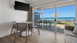 A modern room with a balcony, a dining area with chairs and a table, and a sofa.