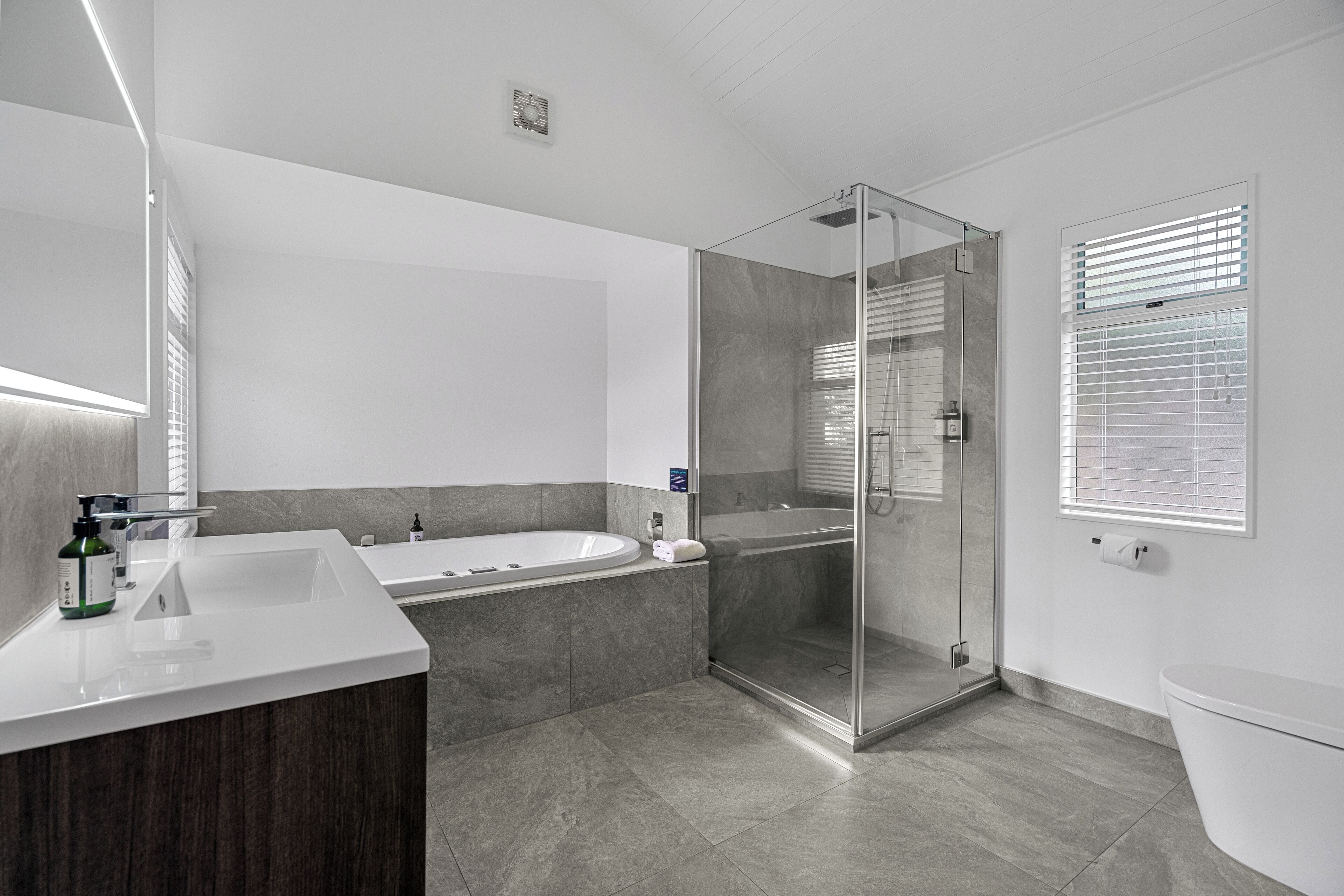 A modern bathroom with a glass-enclosed shower, a freestanding bathtub, and a vanity with a mirror.