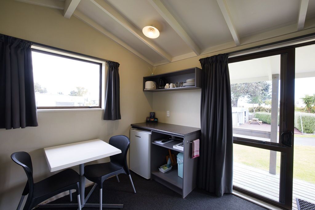 A compact room with a kitchenette, a small dining table, and chairs.