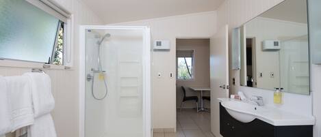 Un baño moderno con cabina de ducha de vidrio, un lavabo blanco y un espejo grande.