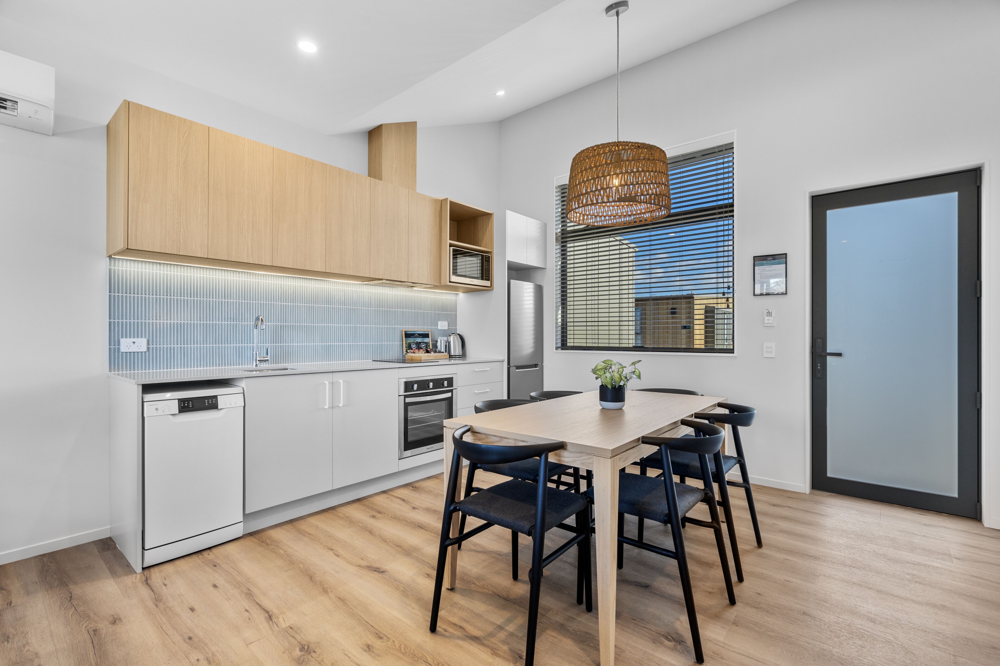 A modern kitchen with white cabinetry, a wooden dining table, and black chairs.