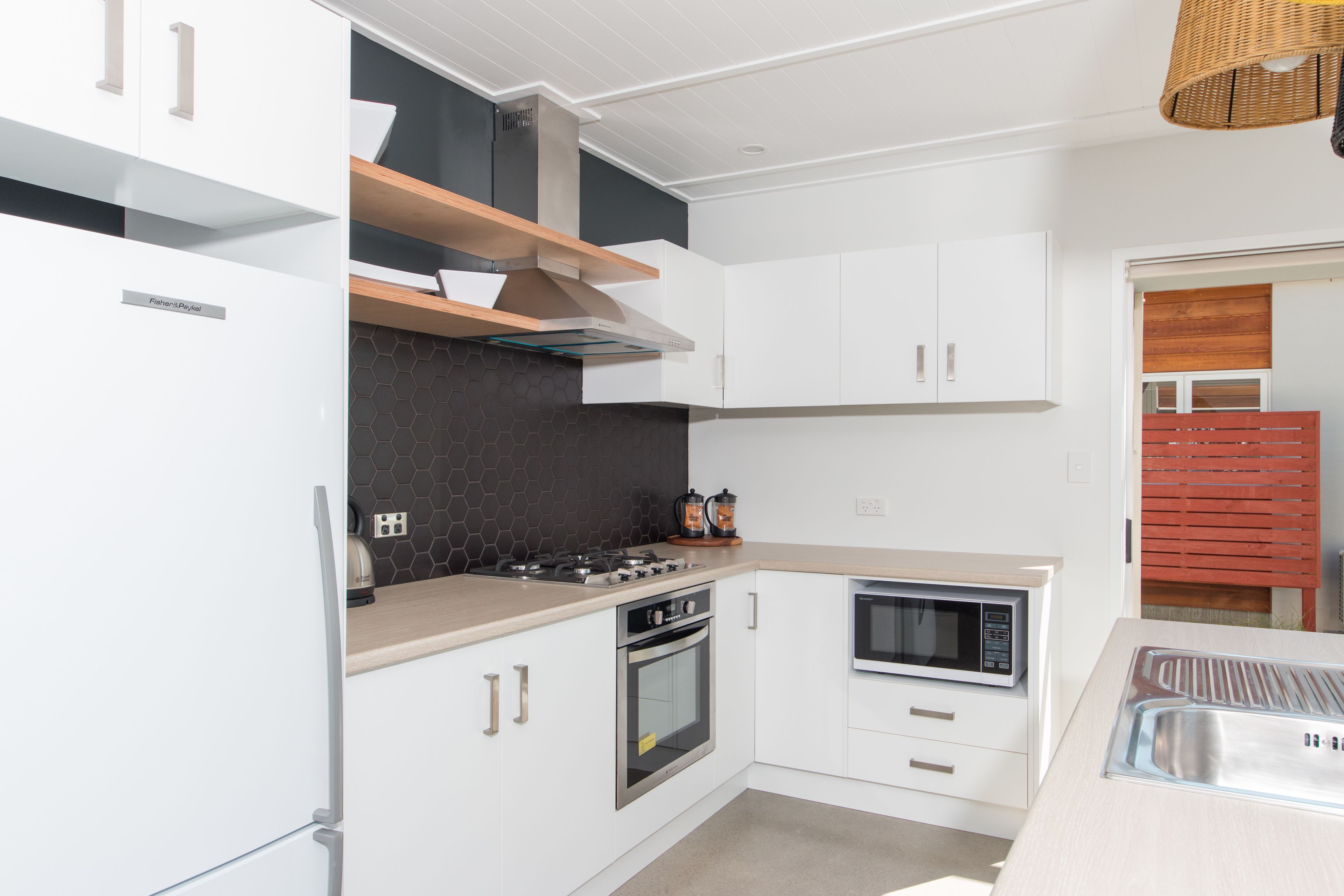 Een moderne keuken met witte kasten, een inbouwoven, magnetron en gasfornuis.