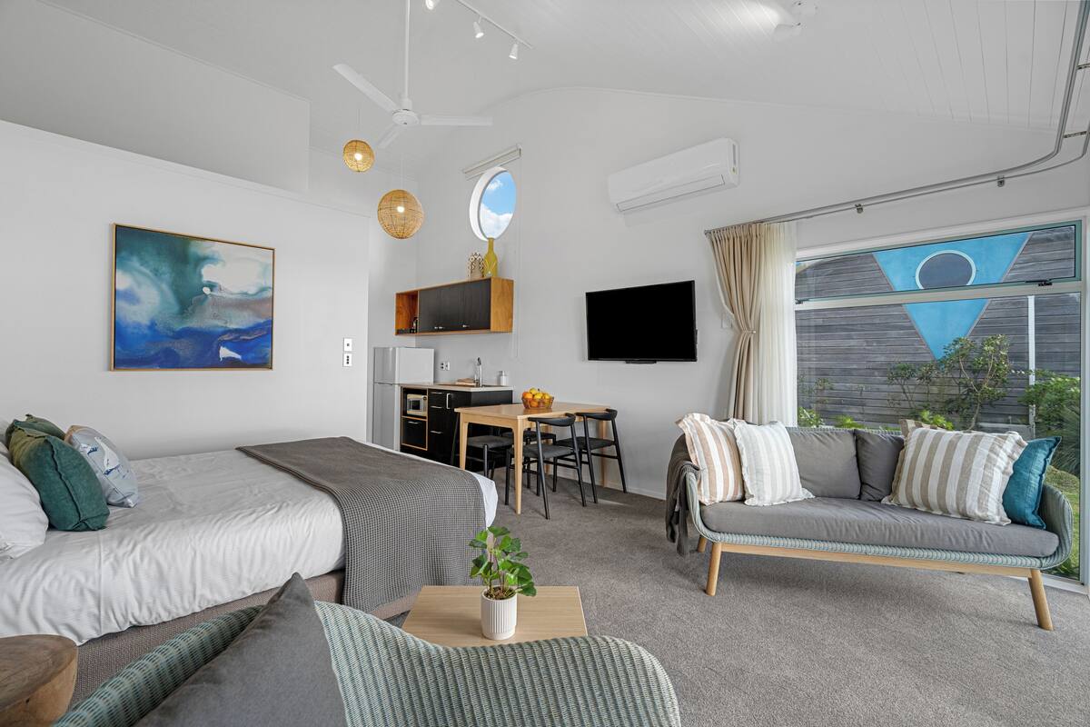 Ein modernes Zimmer mit zwei Betten, einer Couch, einer Essecke und einem Fernseher.
