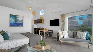 Una habitación moderna con dos camas, un sofá, una zona de comedor y un televisor.