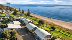 A coastal RV park with multiple RVs, a beach, and a mountainous backdrop.