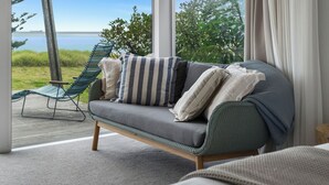 A modern living room with a grey sofa, striped pillows, and a green chair.