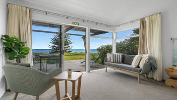 A room with a view of the sea, a sofa, a chair, and a small table.