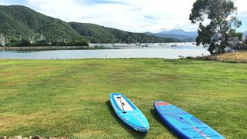 Dos tablas de paddle surf sobre un campo de césped, con un lago y montañas al fondo.