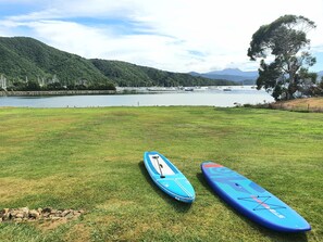 Two paddleboards on a grassy field with a lake and mountains in the background. - Bay Vista Waterfront Motel Picton (Picton)