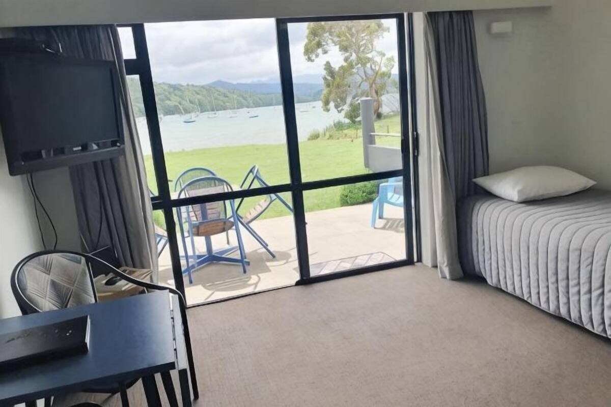 Une chambre avec un lit, un bureau, une chaise, une télévision et une vue sur un lac.