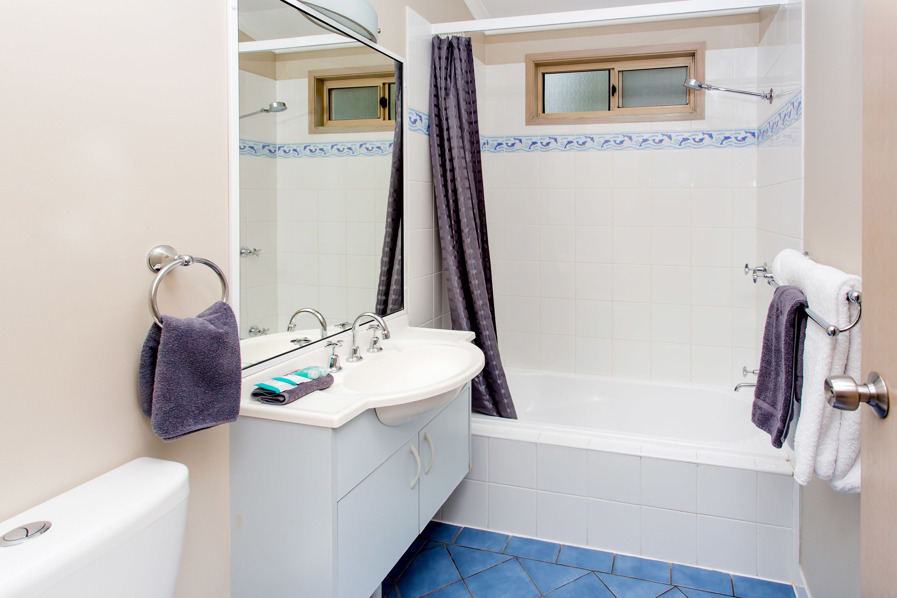 A bathroom with a white sink, a bathtub, a toilet, and a mirror.