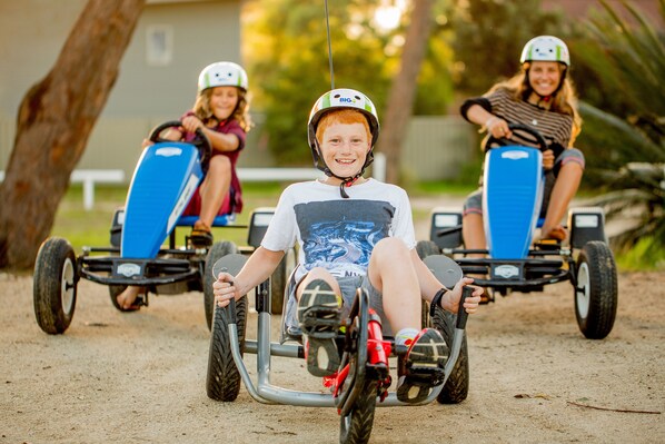 Três crianças a andar num kart.