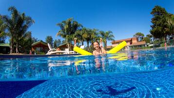 Relax by the serene pool surrounded by lush palm trees and a charming building.