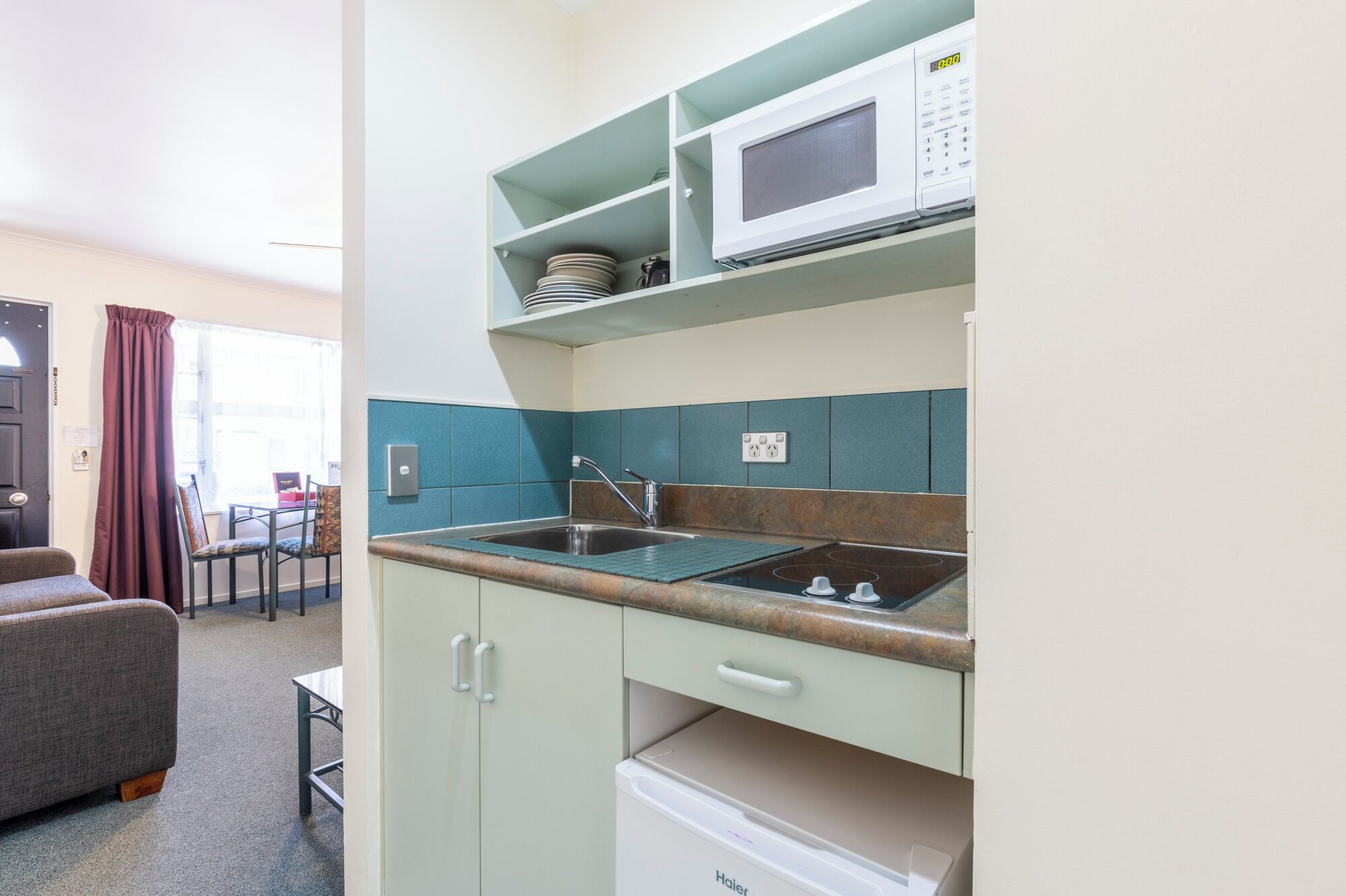 A compact kitchenette with a microwave, a sink, and a built-in oven.