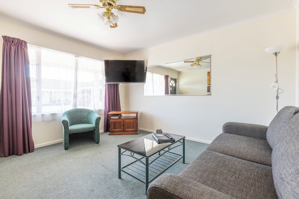 Un salon comprenant un canapé, un fauteuil, une table basse, un téléviseur et un ventilateur de plafond.