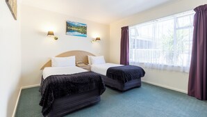 A hotel room with two beds, a large window with curtains, a painting on the wall, and two wall-mounted lamps. - ASURE Prince Motor Lodge (Taupo)