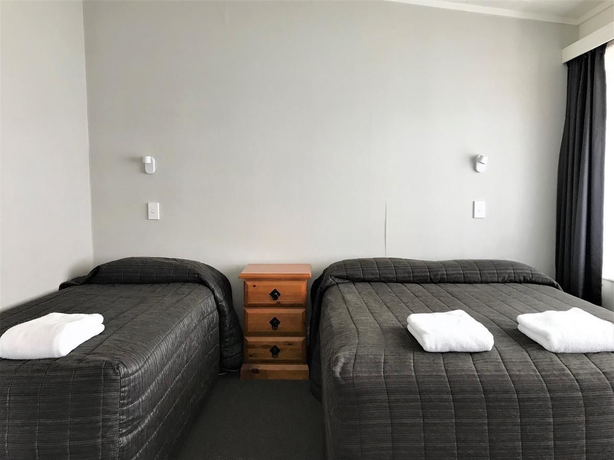 A hotel room with two beds, a wooden dresser, and a window with curtains.