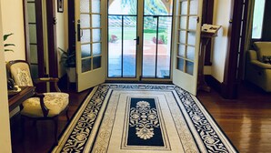 A hallway with a patterned rug, a chair, and a door leading to an outdoor area. - Barossa House (Tanunda)