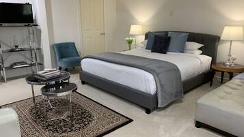 Une chambre moderne avec un grand lit, des tables de chevet, une télévision et un fauteuil.