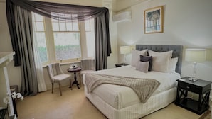 A neatly arranged hotel room with a bed, two bedside tables with lamps, a chair, and a window with curtains. - Barossa House (Tanunda)