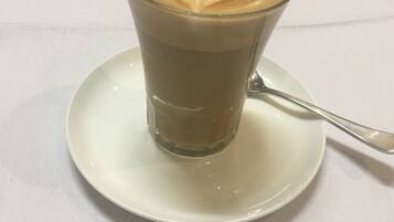 A glass of coffee with latte art on a white plate.