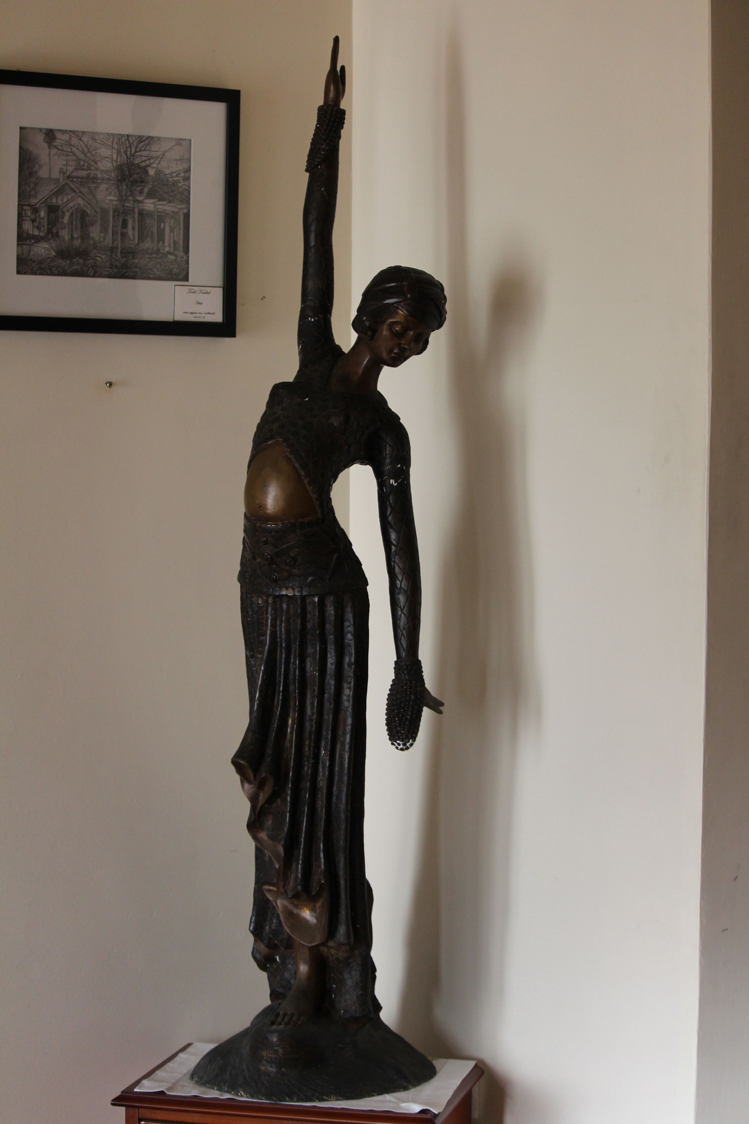 Una estatua de una mujer con un vestido largo y un brazo levantado, sobre un pedestal.