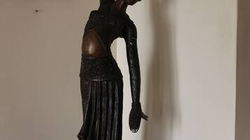 Una estatua de una mujer con un vestido largo y un brazo levantado, sobre un pedestal.
