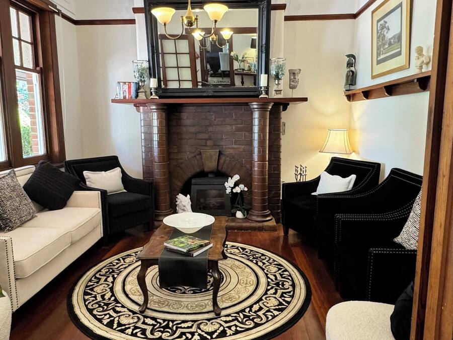 A living room with a fireplace, two black armchairs, a white sofa, and a coffee table.