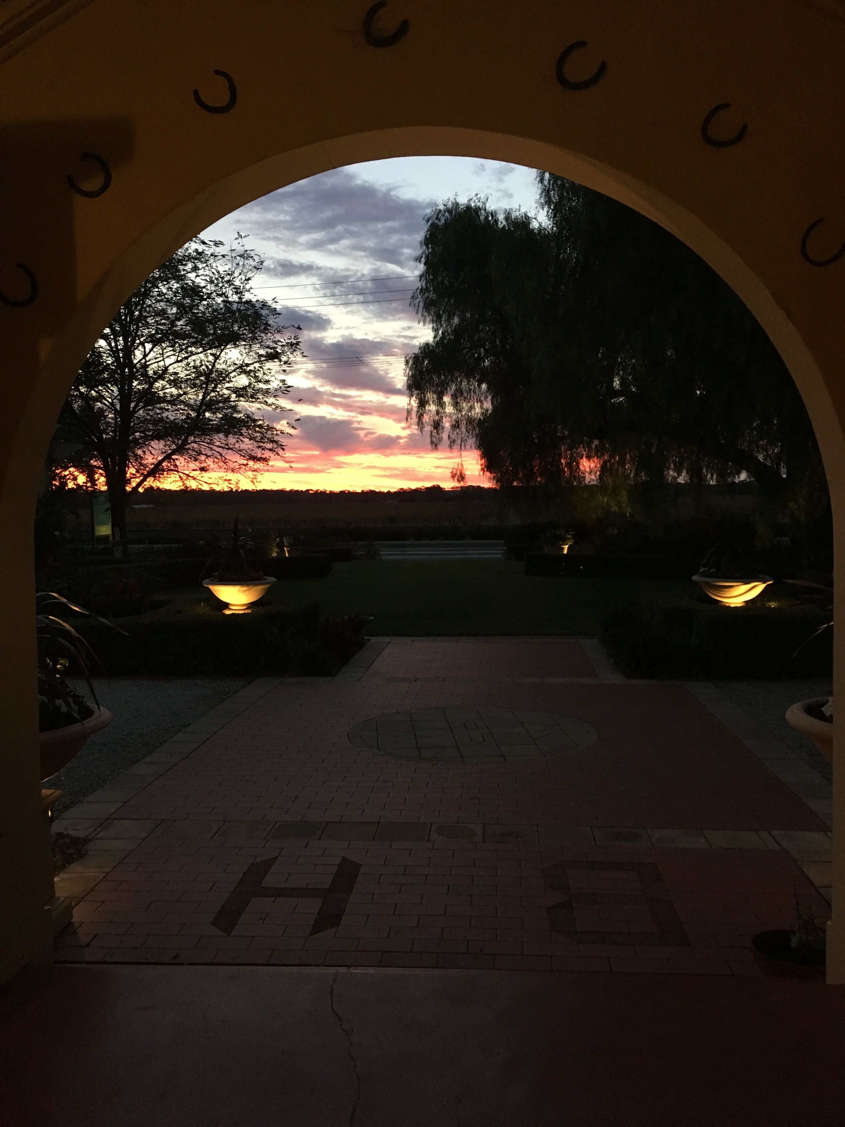 An archway leading to a sunset view with a paved walkway and illuminated planters.