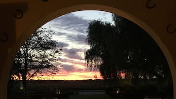 An archway leading to a sunset view with a paved walkway and illuminated planters.