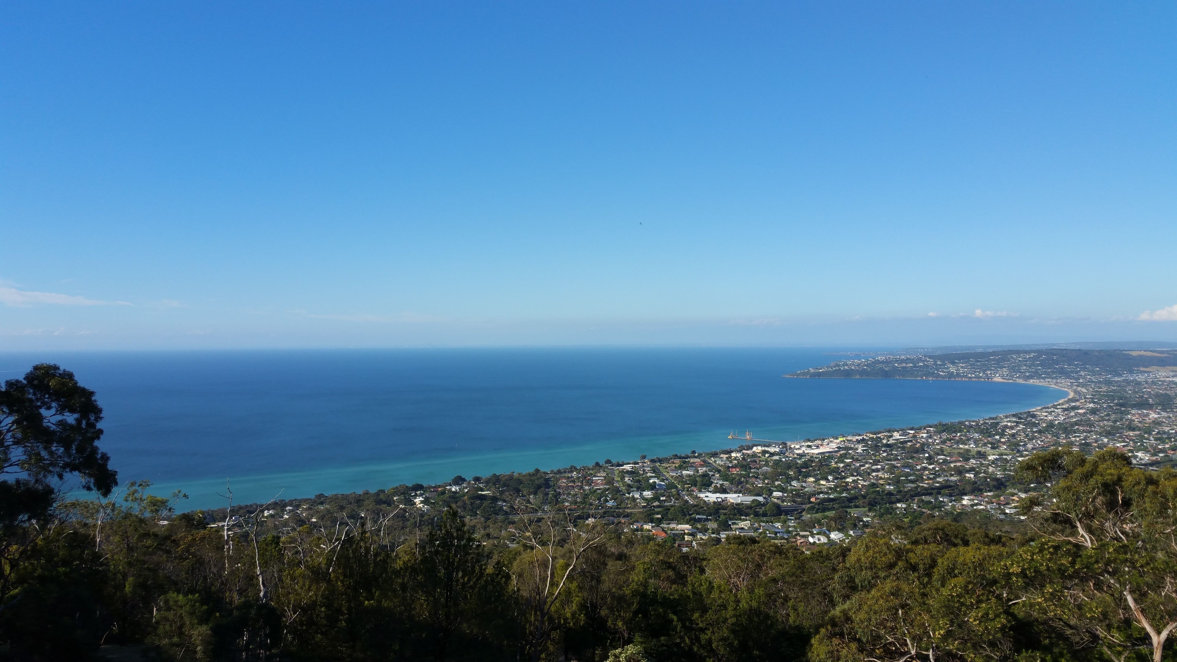 A coastal town with a clear view of the ocean and a bridge connecting the land to the sea.