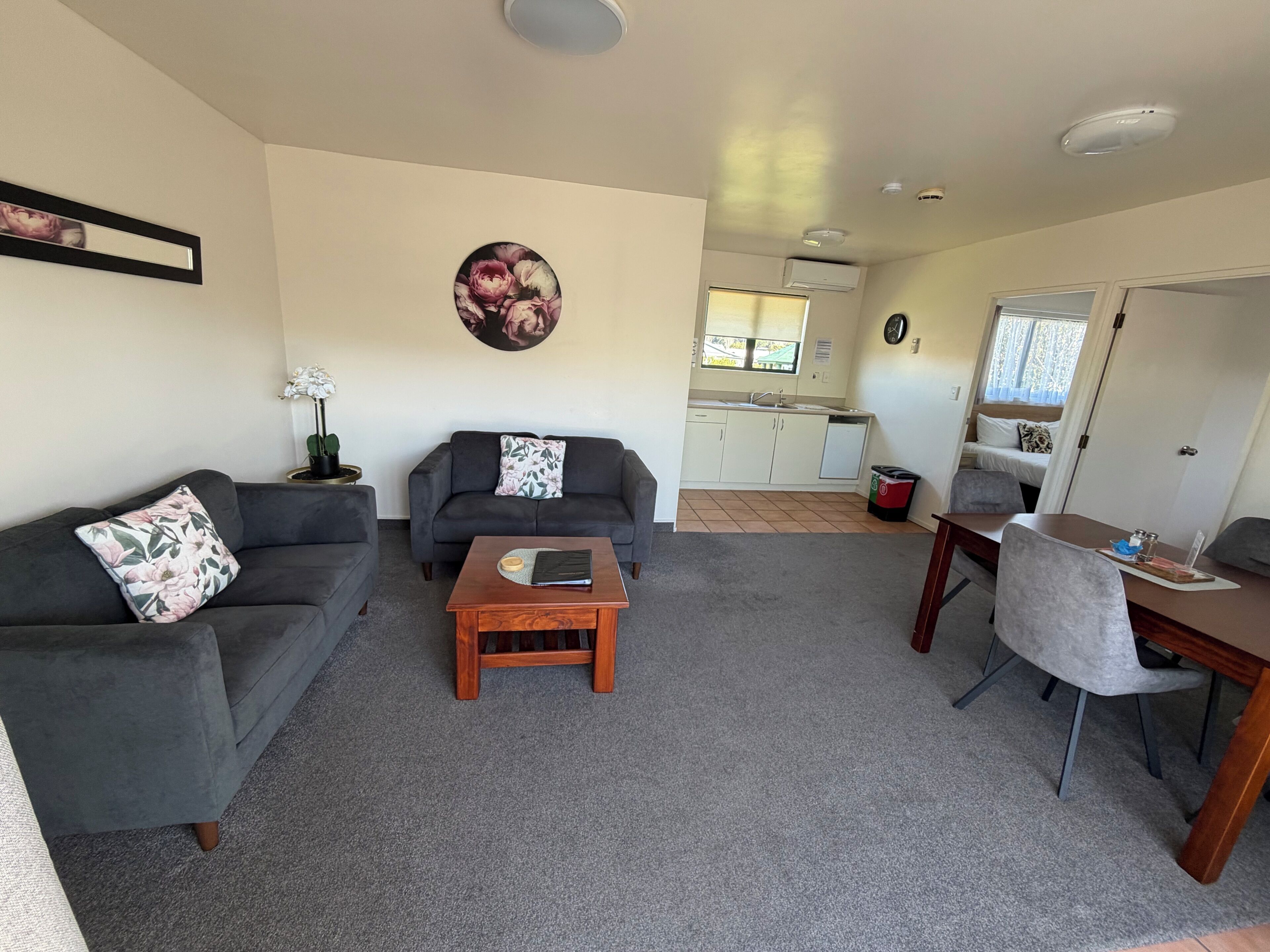 A living room with a sofa, a coffee table, and a dining area with a table and chairs.