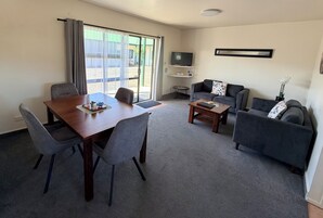 Una sala de estar con una mesa de comedor, dos sofás, un televisor y un ventanal corredizo.