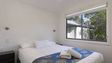 A bedroom with a bed, a window, and a nightstand.
