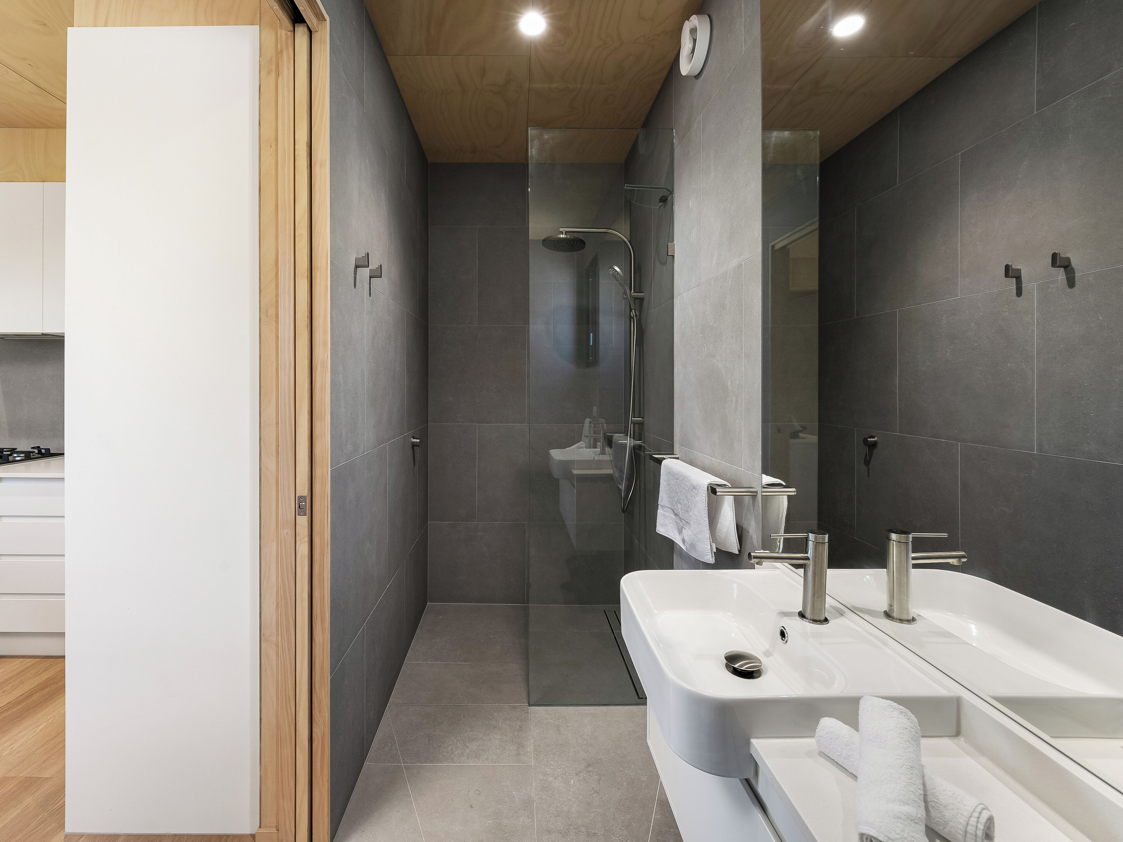 Un baño moderno con ducha, dos lavamanos y un espejo grande.