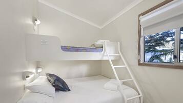 A bunk bed with a ladder, white bedding, and a window with a view of palm trees.